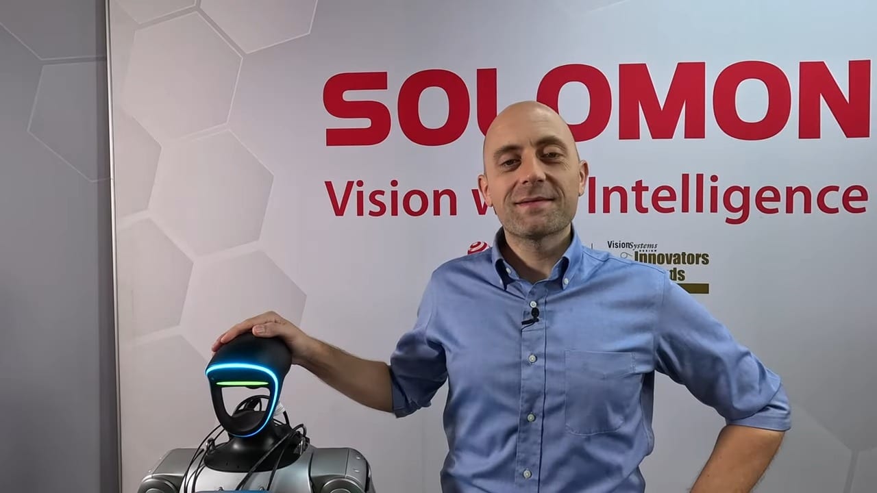 YouTube video thumbnail of Kyle from Solomon Technology standing next to the Solomon humanoid robot. Kyle is wearing a blue shirt, and the robot is silver.